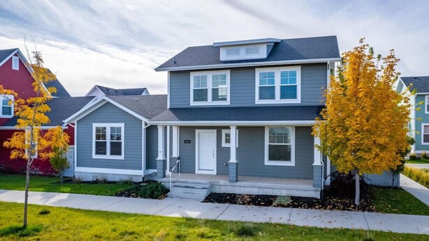 A two-story residential house with a front porch, a garage, and a well-maintained lawn. - Mountain View Daybreak Home | Pets Welcome (South Jordan)
