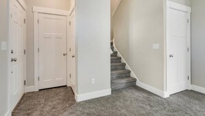 A hallway with two white doors, a carpeted staircase, and a light-colored wall. - Mountain View Daybreak Home | Pets Welcome (South Jordan)