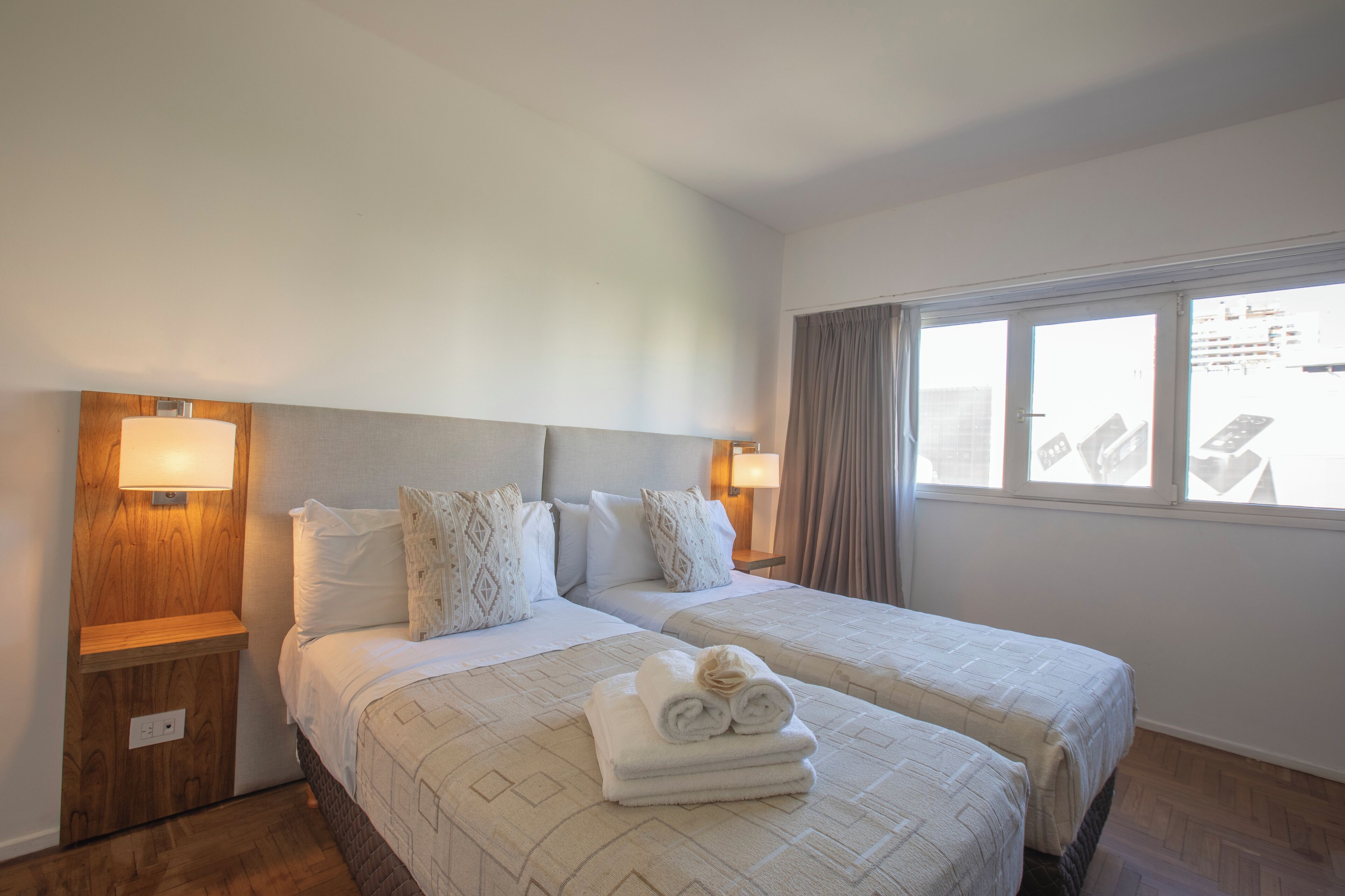 A hotel room with two beds, wooden headboards, and bedside lamps.