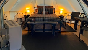 Una tenda con un letto, due comodini, una sedia e un tavolo con una lampada.