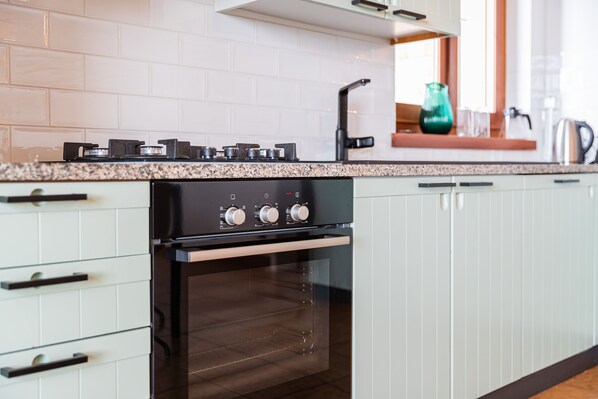 A modern kitchen with white cabinets, a stainless steel oven, and a granite countertop.