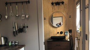A kitchen with wooden cabinets, a countertop, and various utensils hanging above.