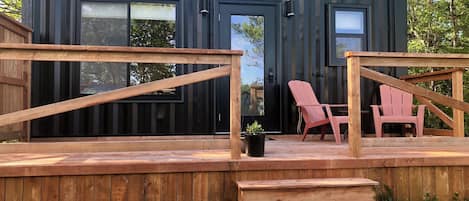 A modern, compact cabin with a deck, two windows, and a door.
