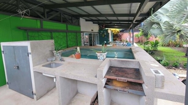 An outdoor pool area with a concrete bar, a door, and a green wall.