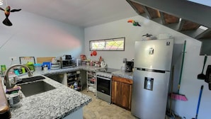 A compact kitchen with a built-in oven, microwave, and stainless steel refrigerator.