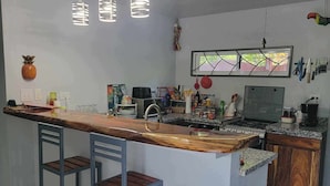 A kitchen with a central island, bar stools, a ceiling fan, and a window with a view.
