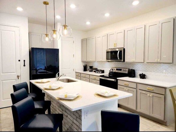 Una cocina moderna con armarios blancos, una isla central e iluminación colgante.