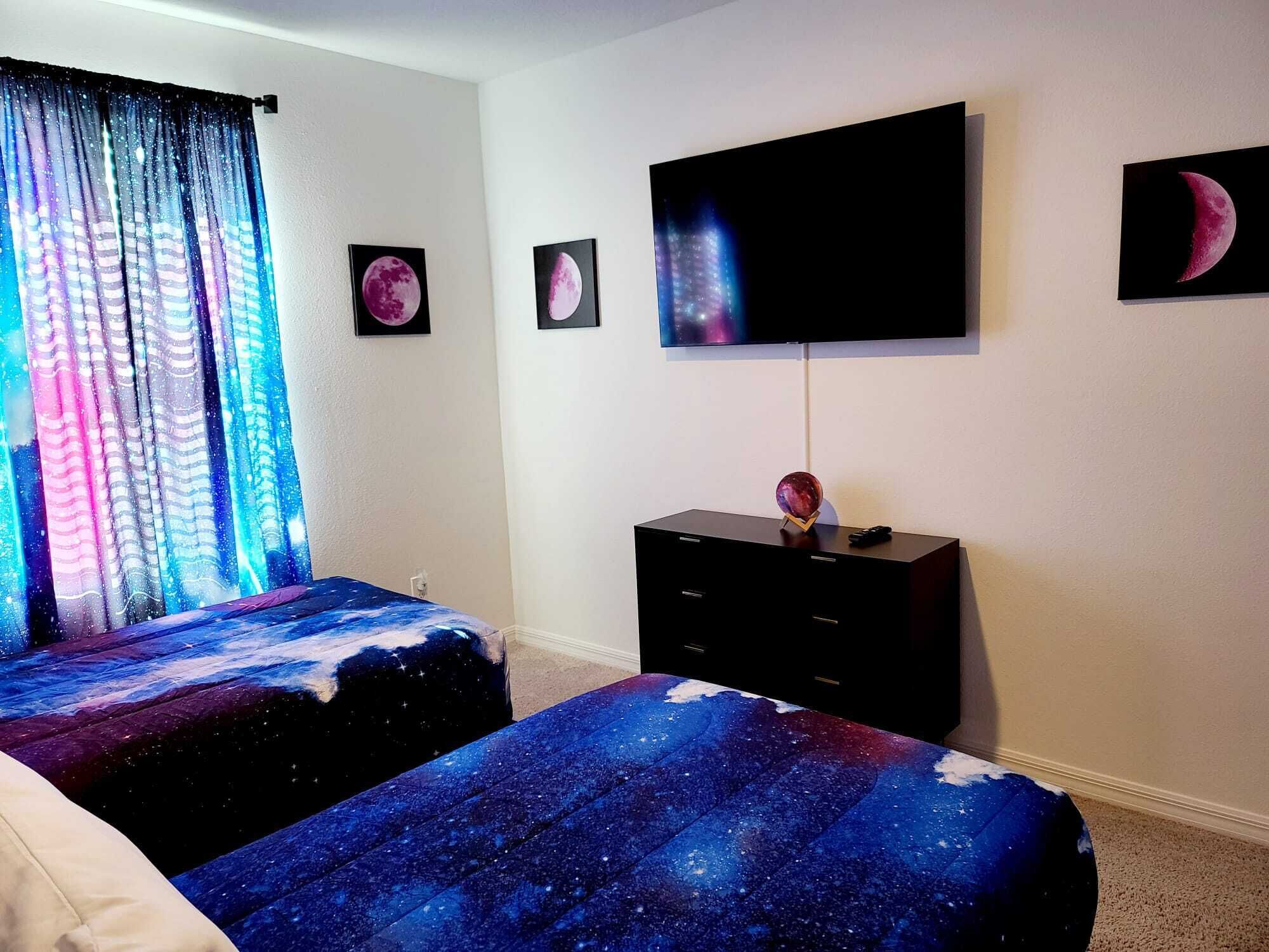 A bedroom with two beds, a TV, and a dresser.