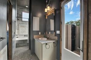 Un baño con un ventanal amplio, una bañera y un tocador con espejo.
