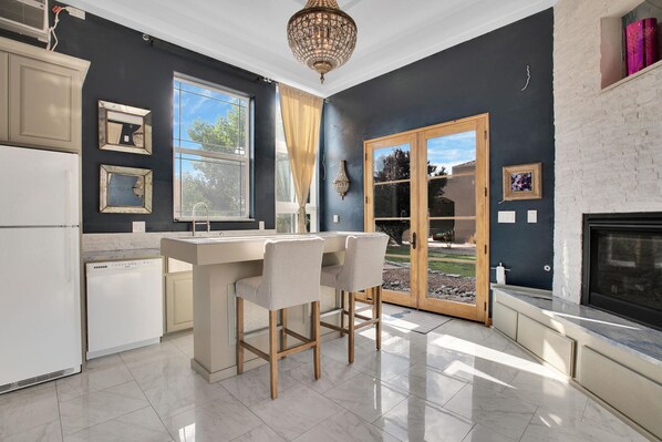 A modern kitchen with a bar area, large windows, and a fireplace.