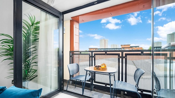 A balcony with a glass door, two chairs, a small round table with fruit, and a potted plant. - 2 Bed Apartment - City Centre - Parking - Balcony
 (Birmingham)