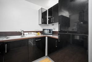 A modern kitchen with dark cabinetry, a stainless steel sink, and a microwave. - 2 Bed Apartment - City Centre - Parking - Balcony
 (Birmingham)