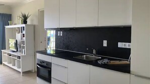 A modern kitchen with white cabinets, a black countertop, and a built-in oven.
