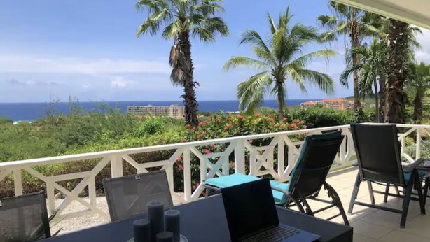 A balcony with a laptop, chairs, and a table with candles.