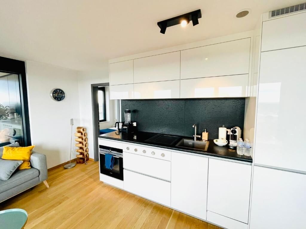 A modern kitchen with white cabinets, a black countertop, and a built-in oven.