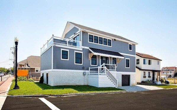 A modern two-story house with a balcony, a staircase, and a solar panel on the roof.