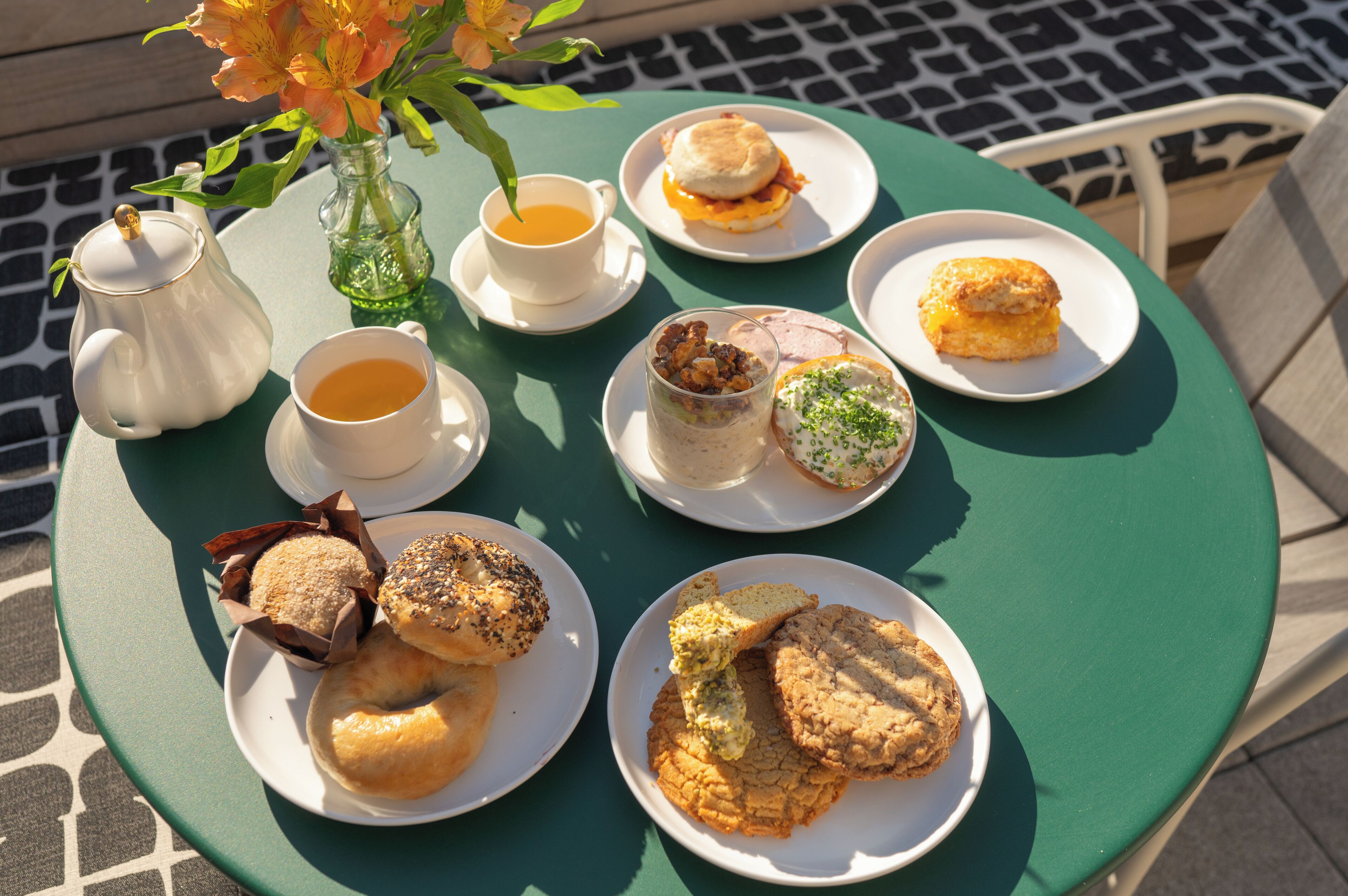 A table with various breakfast items including pastries, sandwiches, and a teapot.