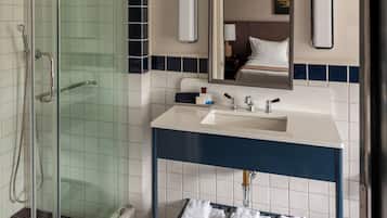A modern bathroom with a glass-enclosed shower, a white sink with a blue countertop, and a mirror above the sink.
