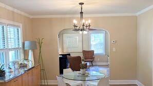 A dining area with a glass table, four chairs, a chandelier, and wooden flooring. - Center of Wilmington-Zen on 42nd-fully fenced yard-Pets ok (Wilmington)