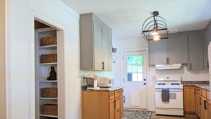 A kitchen with wooden cabinets, a white stove, and a microwave on the countertop. - Center of Wilmington-Zen on 42nd-fully fenced yard-Pets ok (Wilmington)
