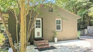 A single-story brick house with a white door and window, a small porch with steps, and a potted plant. - Center of Wilmington-Zen on 42nd-fully fenced yard-Pets ok (Wilmington)