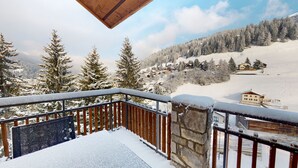 Un balcone imbiancato dalla neve con vista su un paesaggio innevato, che comprende case e alberi.