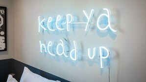 Eine Neonreklame an einer Wand mit der Aufschrift 'keep ya head up'.