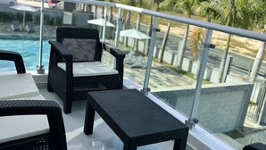 En bar på takterrassen med möbler av rotting, en pool och palmer i bakgrunden.
