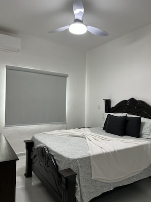 A bedroom with a bed, a ceiling fan, a window, and a nightstand. - A cozy and beautiful apartment in Boca Chica (Boca Chica)
