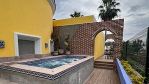 A swimming pool with a tiled border, a brick wall, and a staircase leading to a covered area. - El Encanto Inn (San José del Cabo)