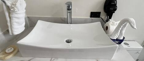 A bathroom with a white sink, a towel rack, a hairdryer, and a soap dish.