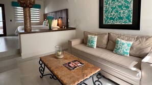 A living room with a sofa, a coffee table, a decorative pillar, and a framed artwork on the wall. - El Encanto Inn (San José del Cabo)