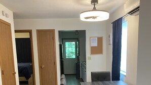 Una stanza con pavimento in legno, un tavolo da pranzo con sedie, una ventola a soffitto e una finestra con tende.