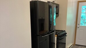 Una cucina con un frigorifero nero, un forno a microonde e un piano cottura.