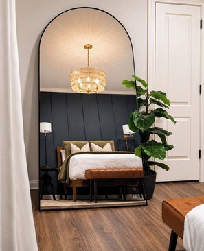 A bedroom with a bed, bedside lamps, a large potted plant, and a wall-mounted mirror. - The Aubrey, 2 Blocks to Square, by Velvet Ditch Villas (Oxford)