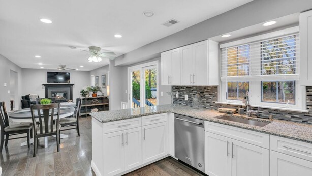 A modern kitchen with white cabinets, granite countertops, and a stainless steel dishwasher. - 5 Bedroom Lavish Summer Oasis with Inground Pool (Ocean Township)