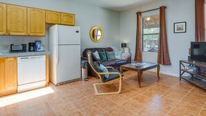 Un espacio habitable compacto con kitchenette, un sofá, un televisor y una mesa de comedor.