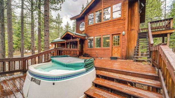 A wooden cabin with a hot tub, wooden deck, and a staircase leading to a deck area. - Deck w/ New Hot Tub (Old Pic): Large TD Home (Truckee)