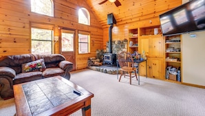 A cozy cabin interior with a fireplace, wooden walls, a leather couch, and a television. - Deck w/ New Hot Tub (Old Pic): Large TD Home (Truckee)