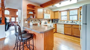 A spacious kitchen with wooden cabinets, a central island with bar stools, and a large window providing natural light. - Deck w/ New Hot Tub (Old Pic): Large TD Home (Truckee)