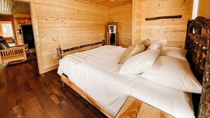 Ein Schlafzimmer einer Holzhütte mit einem Bett, einem Holz-Kopfteil und einem Spiegel.