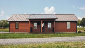 Ein zweistöckiges Holzhaus mit einem Metall-Dach, einer Veranda und einer Schotterauffahrt.
