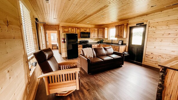 Ein Holzblockhaus mit Wohnzimmer, Küche und Essbereich.