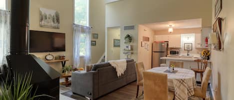 A cozy living room with a fireplace, a sofa, and a dining area with a table and chairs.