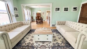 A living room with two beige sofas, a wooden coffee table, and a patterned rug. - The Antique Reno is walking distance to the Falls and in a historic area. (Niagara Falls)