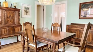 A dining room with a wooden table and chairs, a chandelier, and framed artwork on the walls. - The Antique Reno is walking distance to the Falls and in a historic area. (Niagara Falls)
