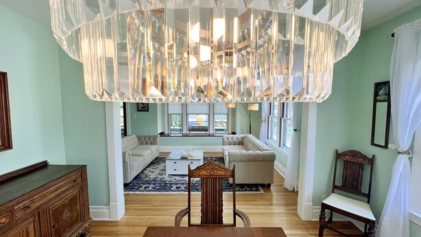 A spacious living room with a large chandelier, a sofa set, and a wooden dining table. - The Antique Reno is walking distance to the Falls and in a historic area. (Niagara Falls)