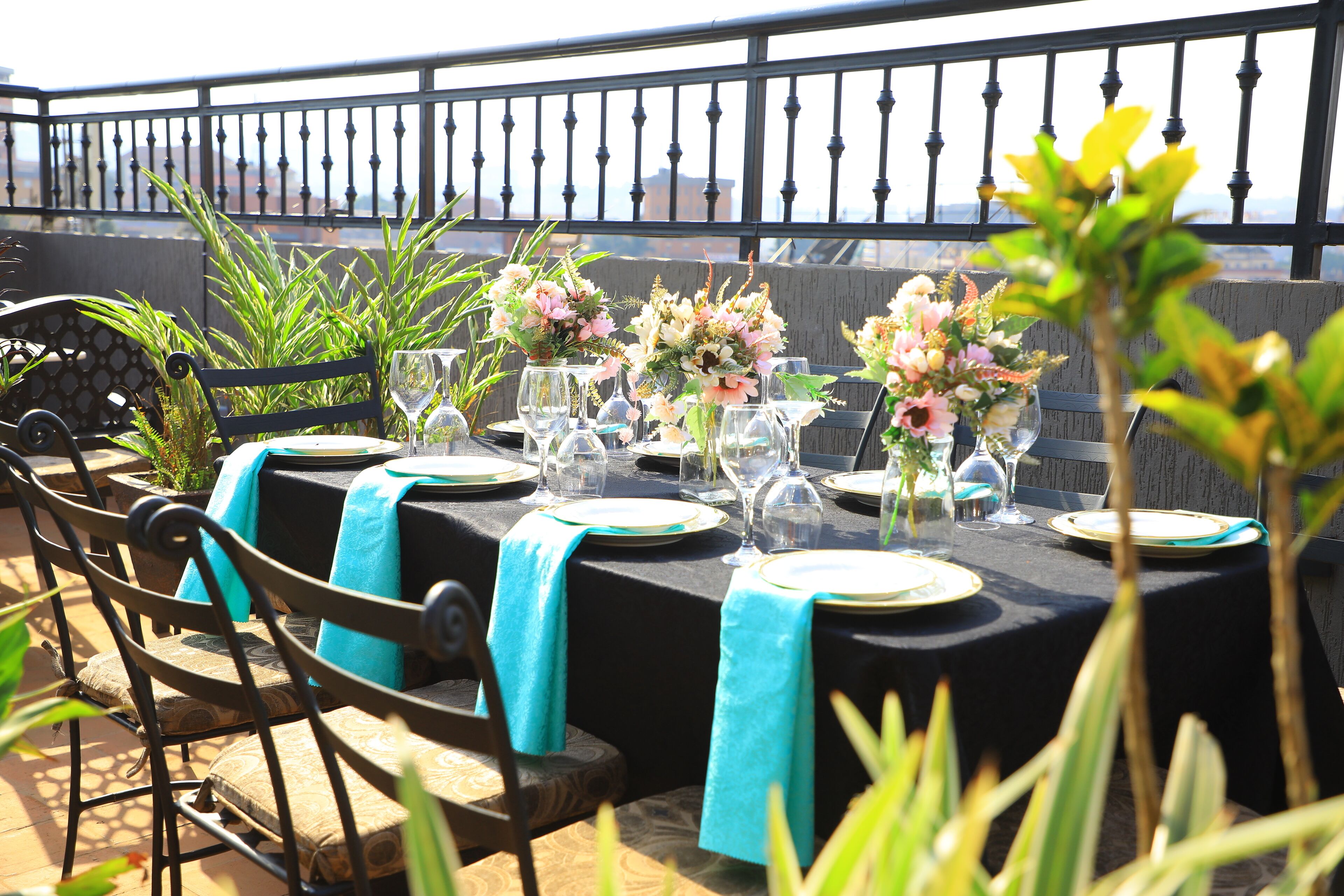 An outdoor dining area with tables set for a meal, surrounded by chairs and potted plants.