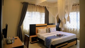 Une chambre à coucher avec un lit, des tables de chevet, un bureau et une chaise.