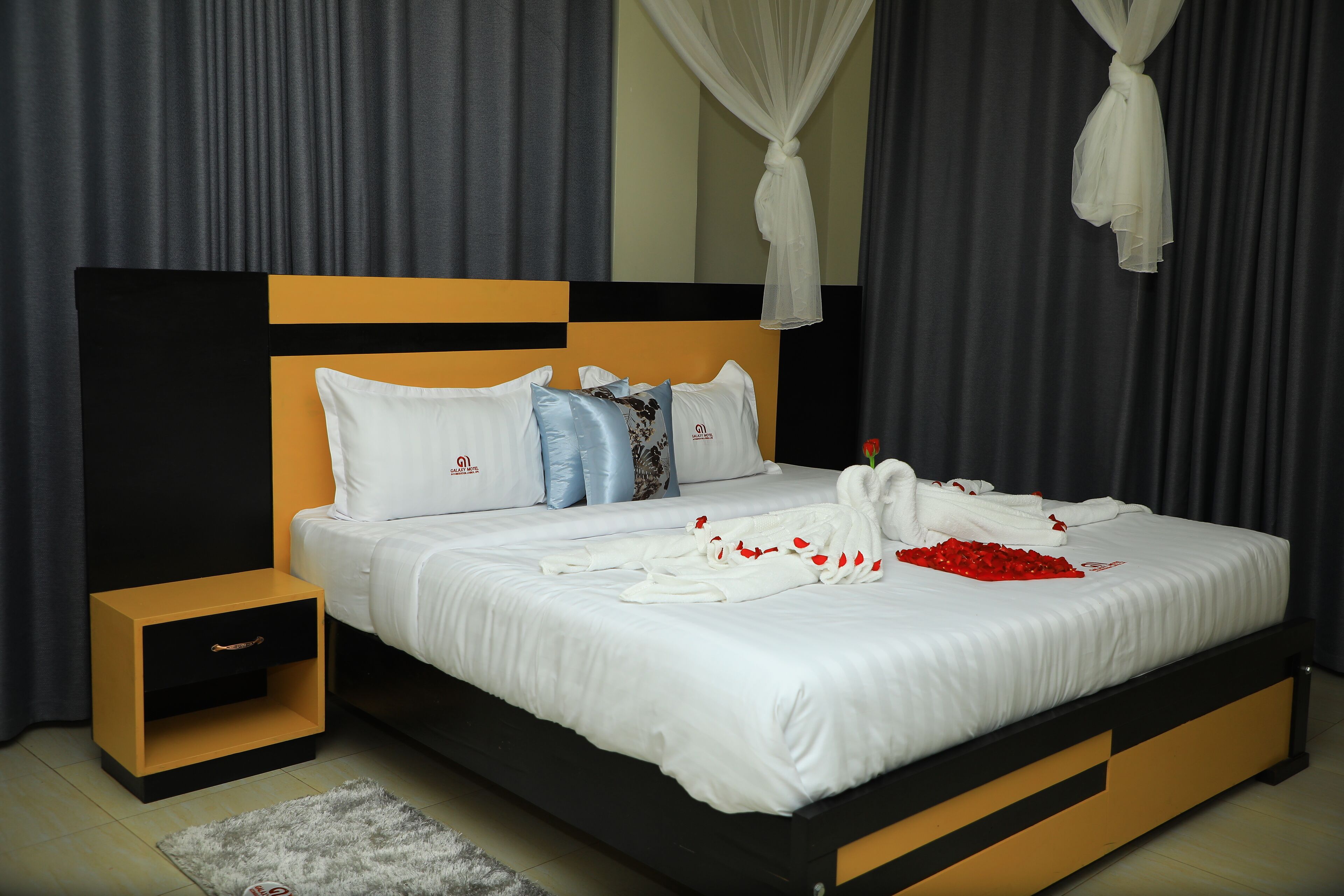 A neatly made bed with white linens, a bedside table, and a small drawer unit.